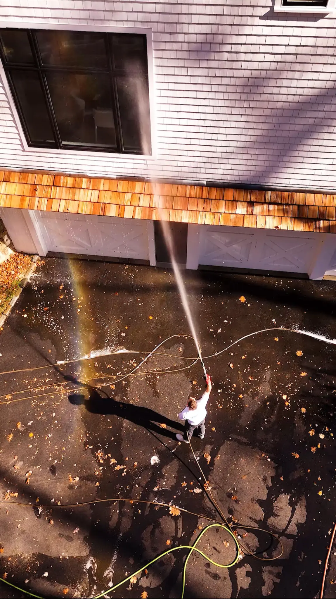 Aerial view of roof washing service showing a rainbow in the mist